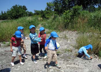 川原で石ころアートに使う石を探す４歳児