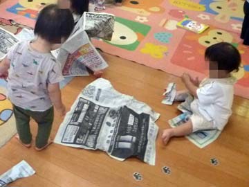 新聞紙をちぎって丸める1歳児