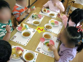 テーブルで、みんなの持ってきた料理を確認しながら、食事を楽しむ園児たち